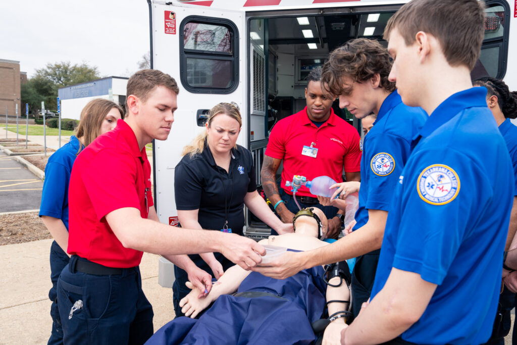 EMT students tend to a patient outside an ambulance.