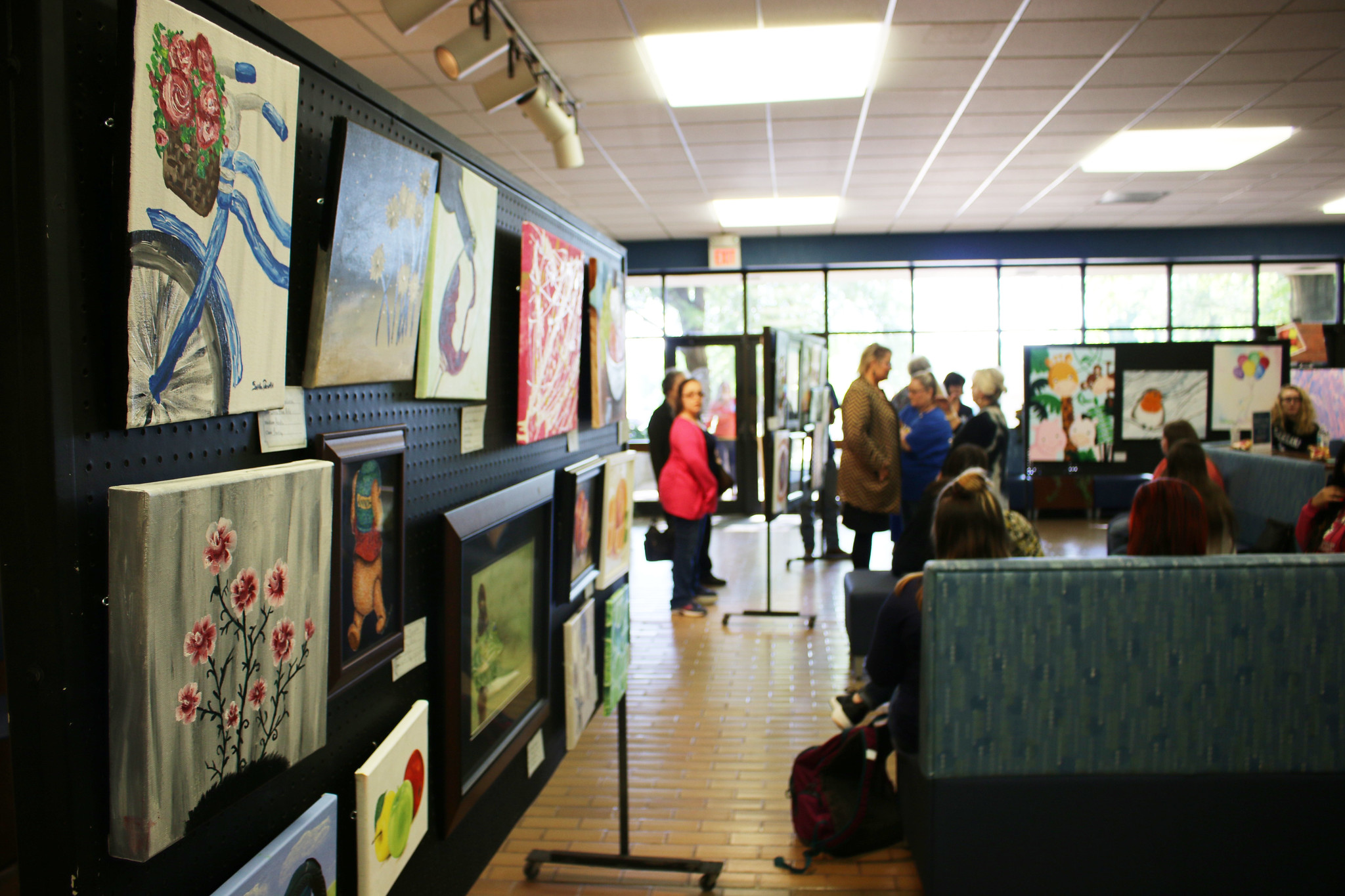 Visitors admire the student art show in the Stilwell Humanities building lobby.